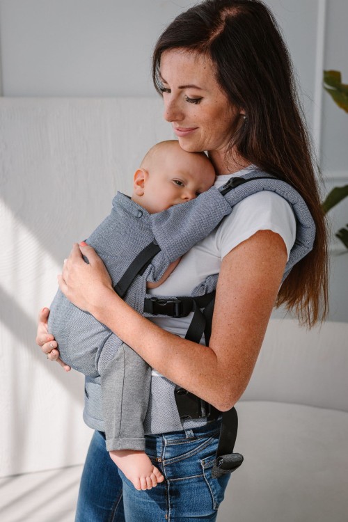 Modelka nosi dziecko w ergonomicznym nosidle KAVKA multi-age ink twill -  niebieskie nosidło z delikatnym wzorem w jodełkę. (a blue carrier with a twill - delicate herringbone pattern.)